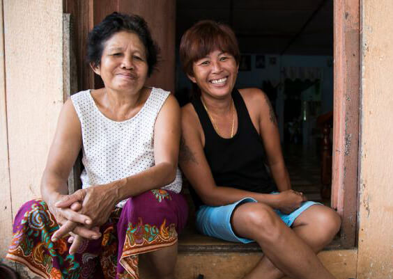 Two women sit leaning together in a doorway.