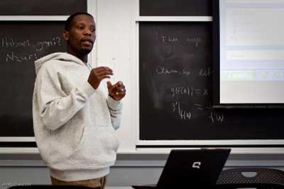 Photo of Bernard Kiwia speaking to students in class.