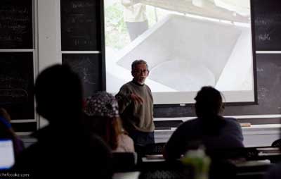 Photo of Suprio Das standing in front of a projected photo of a water well.