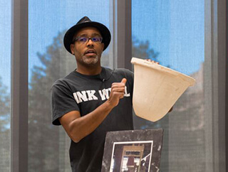 A man holds a bell-shaped ceramic water filter up for display.